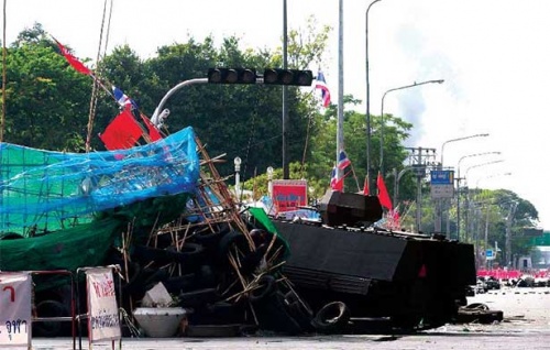 An armoured personnel carrier brings down a red shirt barricade at Sala Daeng Intersection